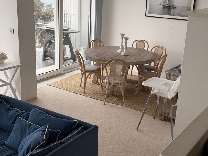 Round dining table with a high chair, beside the deck doors