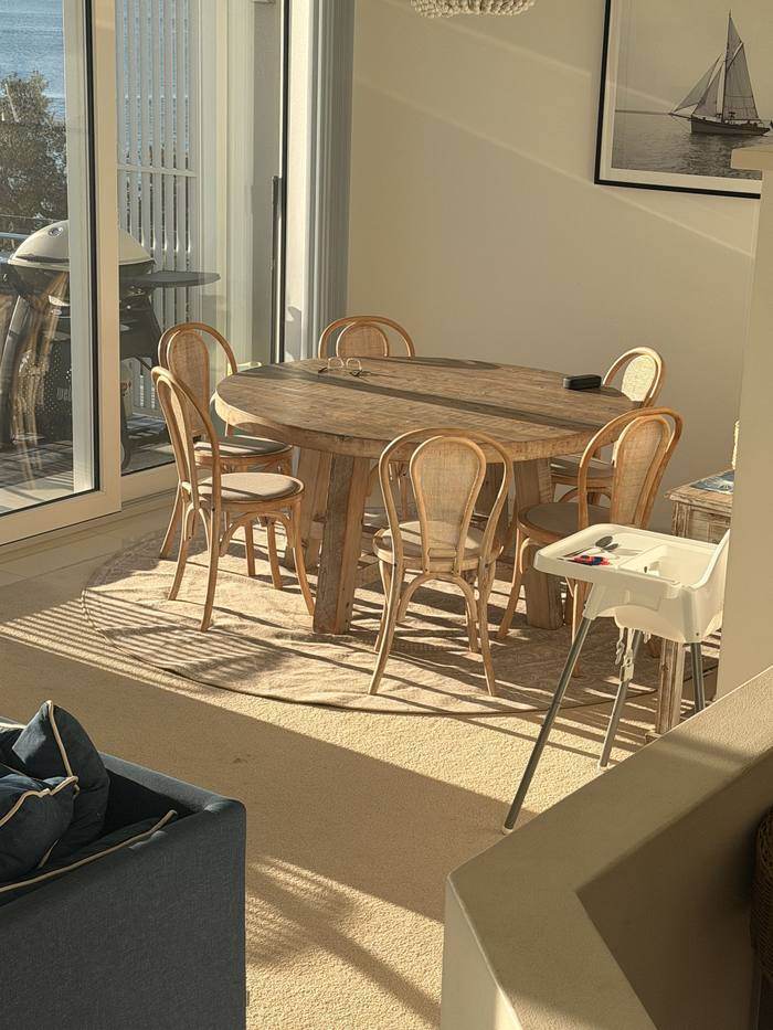 Round timber dining table seating six at Riviera, Nelson Bay